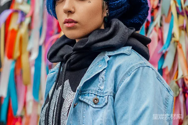 高清摄影 蓝色头发的女子穿着蓝 denim 夹克站在一条装饰有蝴蝶结的长凳旁边。