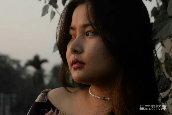 高清摄影 一个女人站在一棵有叶子的树旁边