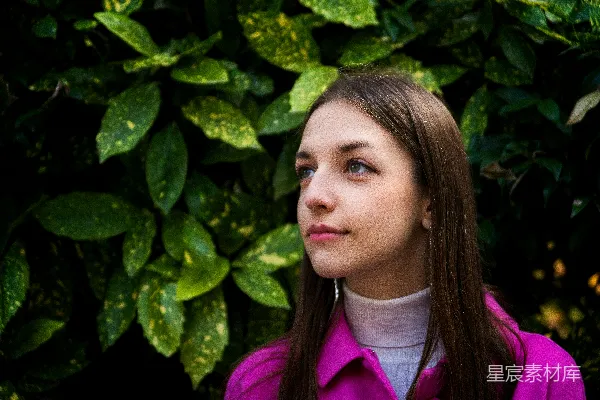 高清摄影 一个穿粉色上衣的女人站在灌木丛前。