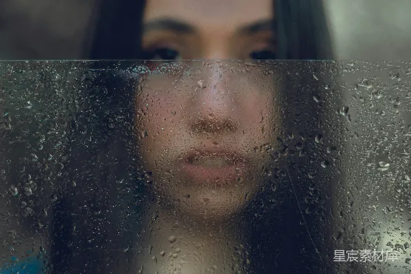 高清摄影 一个女子透过蒙上雨的窗户看外面。