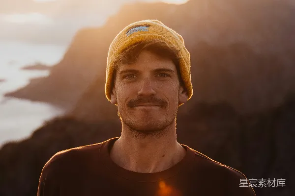 高清摄影 一个戴黄色帽子的男人站在山前。
