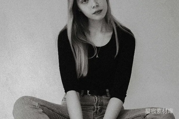 高清摄影 黑色长袖上衣穿着的女子坐在白色的地板上，穿着灰色的牛仔裤。