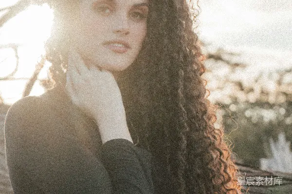 高清摄影 一头长 curly 头发的女子站在一棵树前
