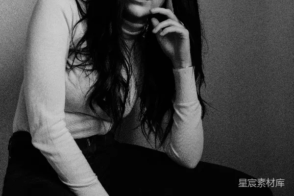 高清摄影 白上衣穿着的女人坐在椅子上，穿着黑色裤子。