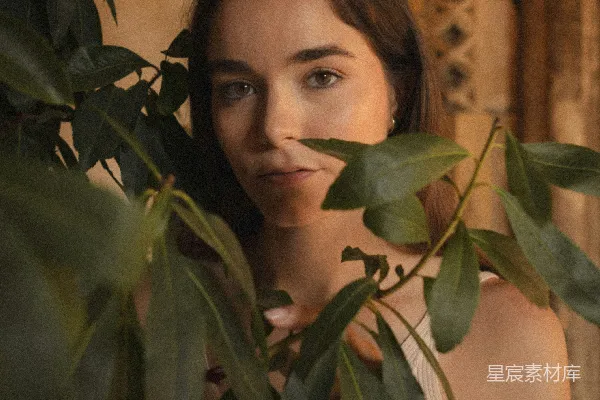 高清摄影 一个女人站在一盆绿色植物旁边。
