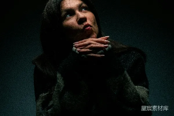 高清摄影 一个女人坐在黑暗中，双手放在胸口。