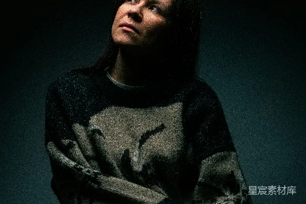 高清摄影 一个女人坐在一间黑暗房间里的椅子上。