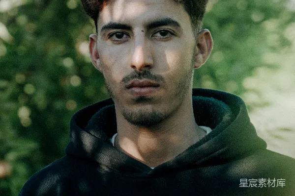 高清摄影 一个穿着黑色卫衣的男人站在一棵树前面