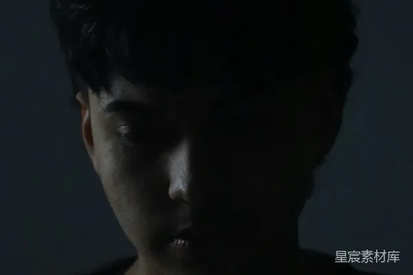 高清摄影 一个男子身处黑暗的房间里，眼睛闭上。