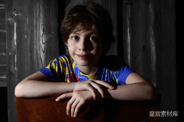 高清摄影 一个年轻男孩坐在椅子上，双手交叉。