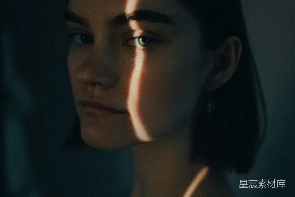 高清摄影 黑暗房间中的一个女子，灯光照亮她的脸。