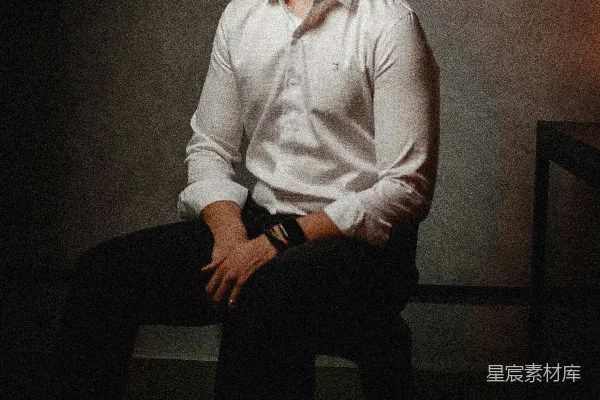 高清摄影 一个男人坐在一间黑暗房间里的椅子上。