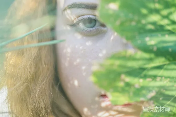 高清摄影 一个蓝眼睛的女人正在拿着一片绿叶。
