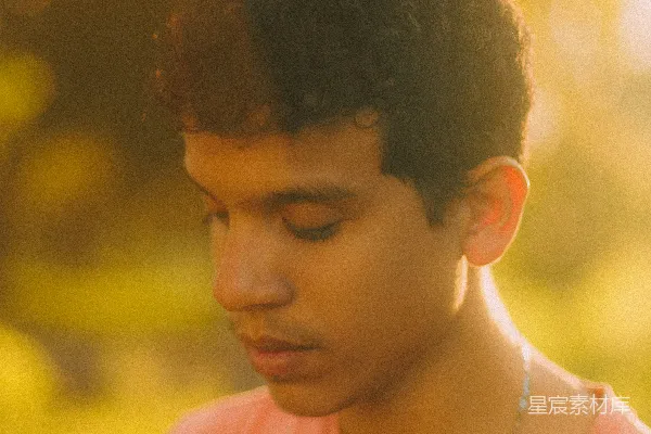 高清摄影 金光下低头的 curly 头青年。