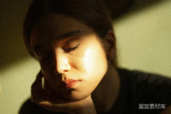 高清摄影 一个女子坐在黑暗的房间里，眼睛闭着。