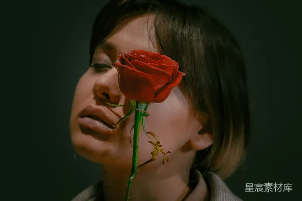 高清摄影 灰白条纹长袖上衣的女人正拿着一朵红玫瑰。