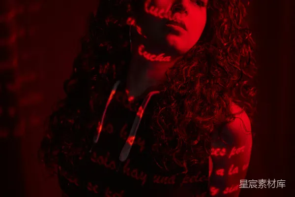 高清摄影 一个长发 curly 改为 wavy 的女性站在一间黑暗的房间里