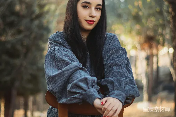 高清摄影 一个女人坐在一张木制椅子的顶部。
