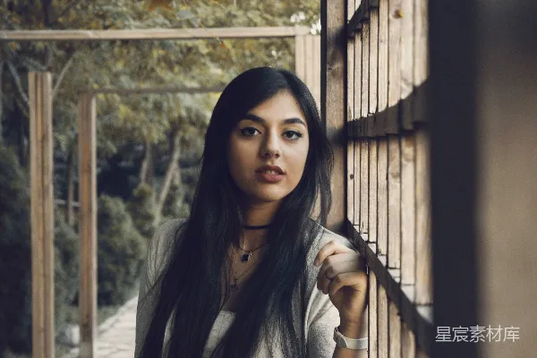 高清摄影 一个女人站在一块木墙旁边。