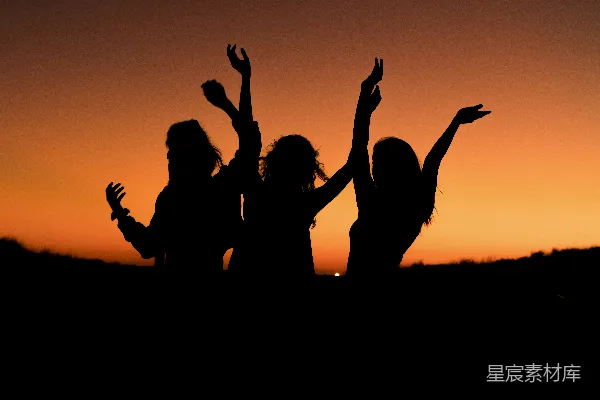 高清摄影 夕阳下三位女性跳舞的轮廓，她们的手在空中轻抚。