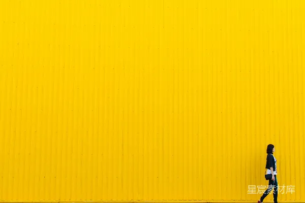 高清摄影 身穿黑色上衣的女人站在黄色的墙边