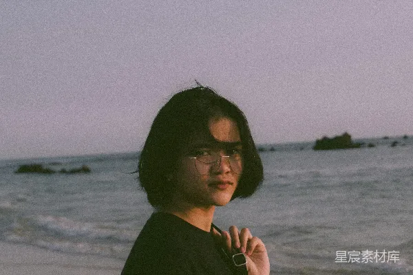 高清摄影 海滩上站着一位女性，旁边是海洋。