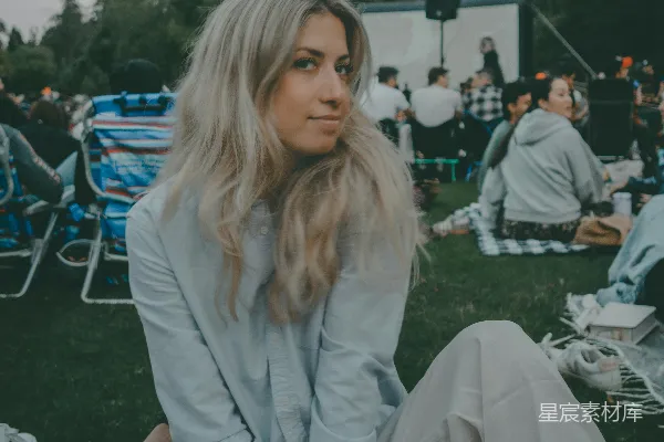 高清摄影 一个女人坐在一群人的前面草地上。