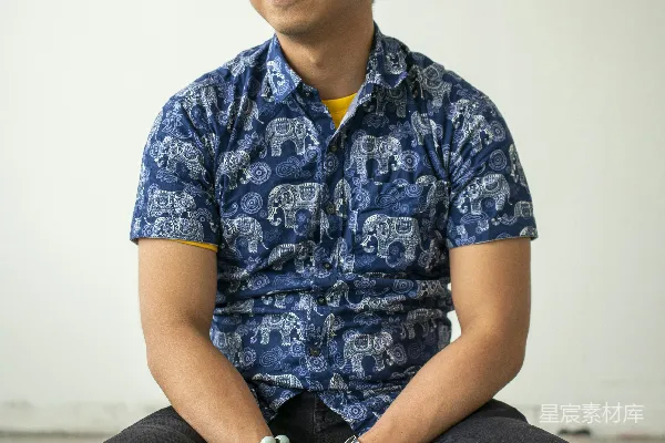 高清摄影 笑眯眯的男人坐在凳子上，侧头望着。