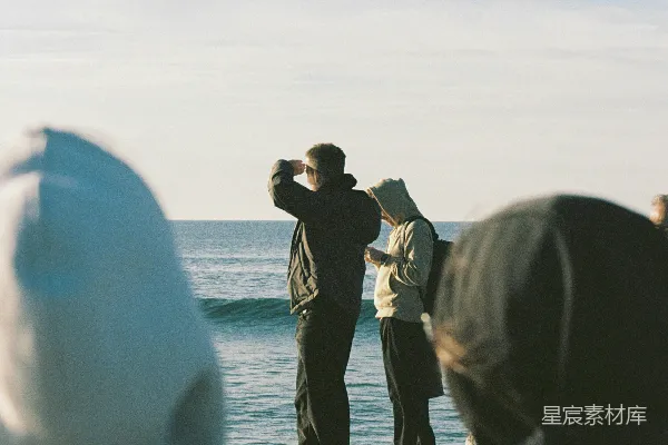 高清摄影 一群人在海滩上站立，旁边是海洋。