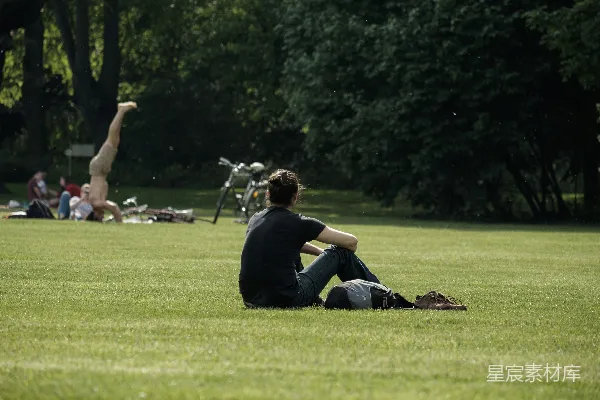 高清摄影 黑T恤男人穿着蓝色牛仔裤坐在绿色草地上的田里