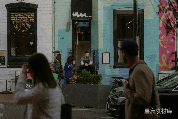 高清摄影 行人走在一条街道的 sidewalk 上，旁边是一家餐馆。