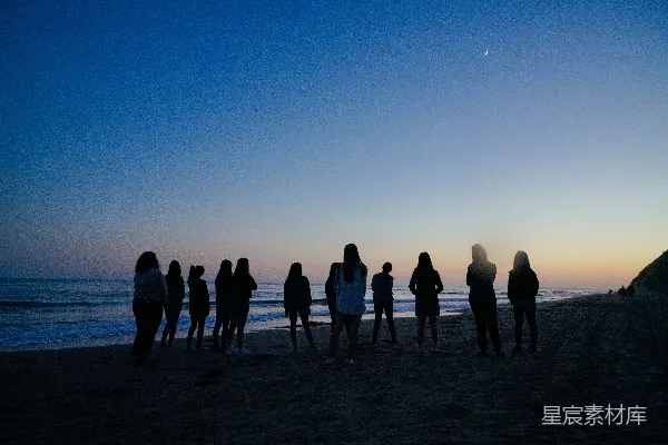 高清摄影 海边的人们在夜间站立。