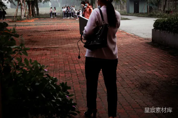 高清摄影 一个女人站在砖砌的小径上，正在打电话。