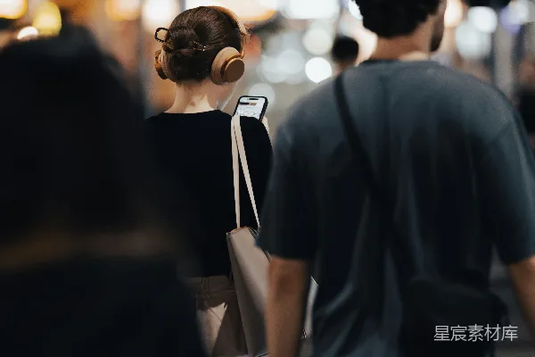 高清摄影 戴着耳机的女人和一个男人走在城市街道上。