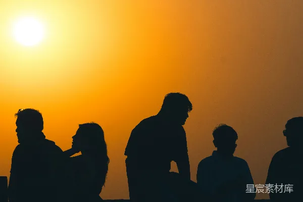 高清摄影 黄昏时分，人们轮廓 against 一片明亮的橙色夕阳。