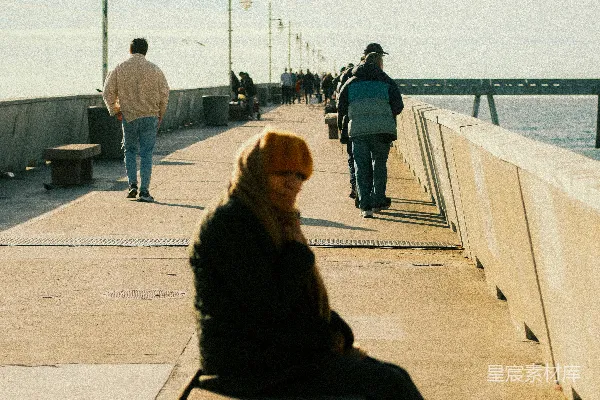 高清摄影 女人坐在码头上，背景中有行人行走。