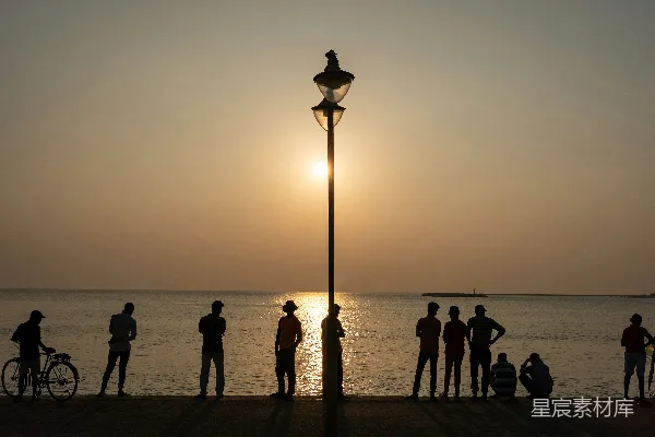 高清摄影 夕阳下水面上轮廓分明的人和路灯。