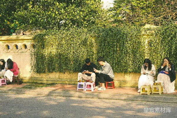 高清摄影 坐在小凳子上的人们聚集在一条小巷里。