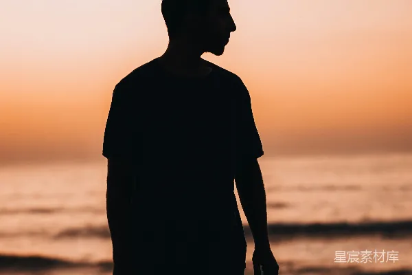 高清摄影 一个男子站在海边的沙滩上，靠近大海。