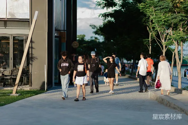 高清摄影 人们走在阳光下的 sunny waterfront promenade 上。