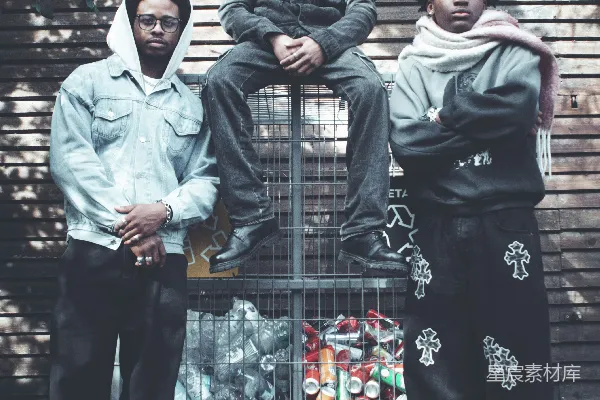 高清摄影 三名年轻人站在一个回收桶前面。