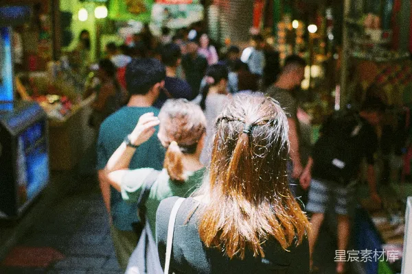 高清摄影 一群人走在街道旁边，旁边有一台电视。