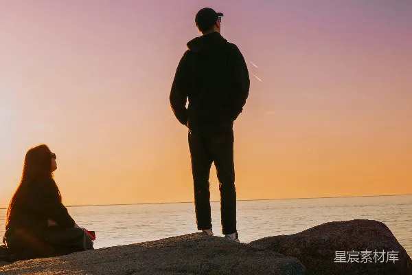 高清摄影 一个男人和一个女人站在岩石旁的海边。