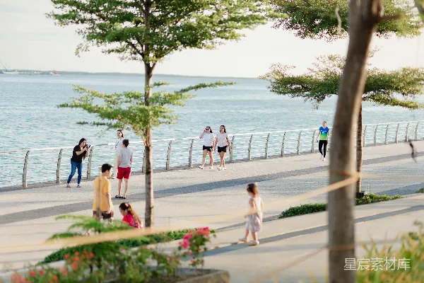 高清摄影 人们在傍晚时分走在 waterfront promenade 上。