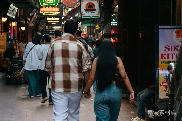 高清摄影 一对夫妇走在有霓虹灯标志的街道上。