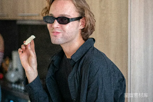 高清摄影 一个穿着黑色上衣和戴着太阳镜的男人正在吃东西。