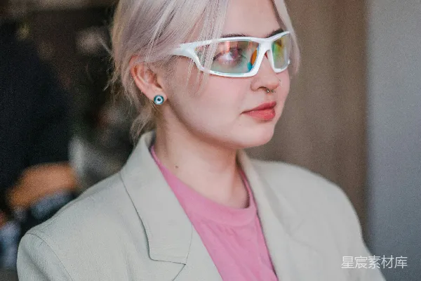 高清摄影 一个穿着西装、戴着太阳镜的女人拿着一杯东西。