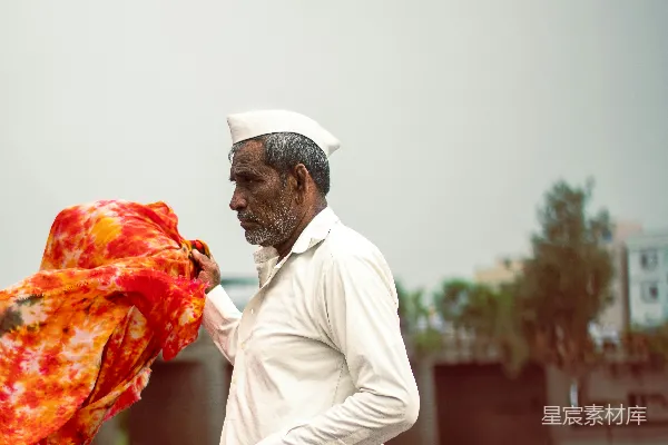 高清摄影 一位老人站在户外手持布料。