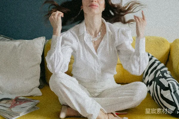 高清摄影 一个女人坐在一张黄色的沙发上，她的头发在风中飘动。