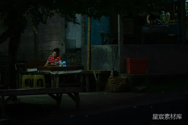 高清摄影 一个男人坐在一张桌子旁，周围是黑暗。